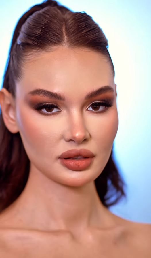 A finished makeup look with a sleek high ponytail